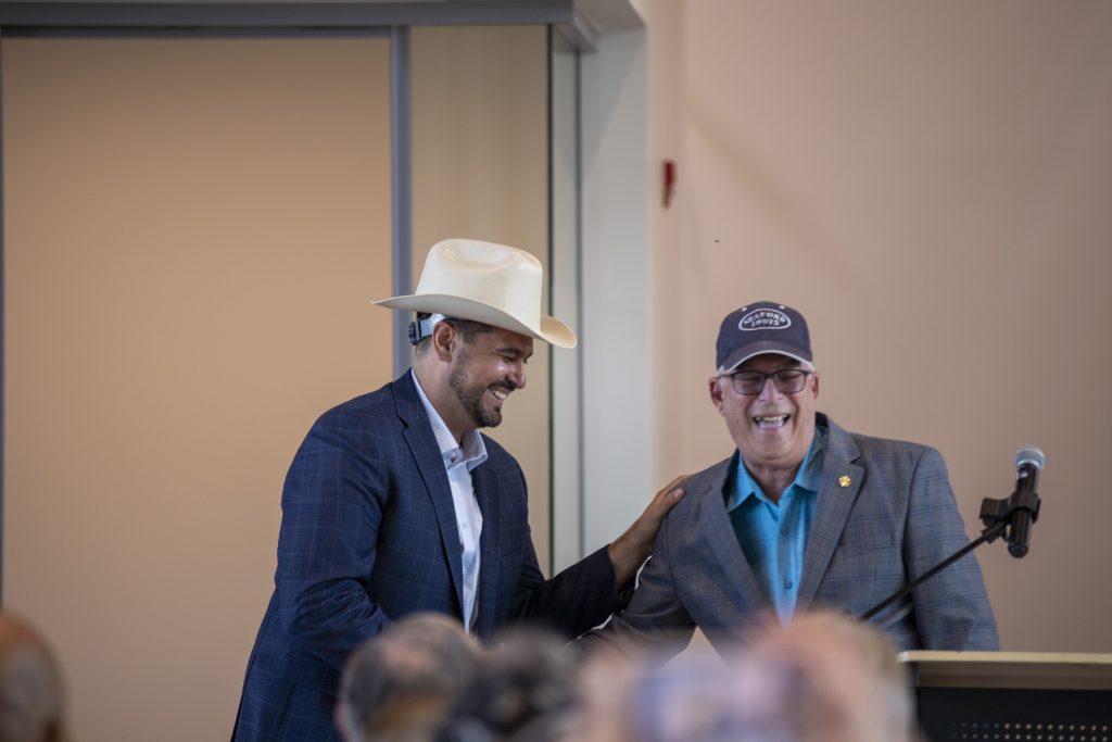 Representative Danny Short speaking at The Mill Seaford Ribbon Cutting Ceremony and giving Robert Herrera a cowboy hat.